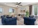 Comfortable living room featuring plush blue sofas, a modern ceiling fan, and an entertainment center at 29243 N 122Nd Ln, Peoria, AZ 85383