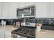 Modern kitchen features stainless steel microwave and range with dark backsplash and light countertops at 35231 N Danburite Ct, San Tan Valley, AZ 85144