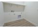 Functional laundry room with built-in shelving and wood-look flooring at 35231 N Danburite Ct, San Tan Valley, AZ 85144