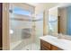 Tiled shower with glass door, a built-in seat, and a window for natural light, complemented by a wooden vanity at 4459 E Donato Dr, Gilbert, AZ 85298