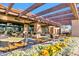 Relaxing outdoor patio area with a wooden pergola, stone columns, and colorful flower beds for serene dining at 4674 E Alfalfa Dr, Gilbert, AZ 85298