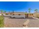 Backyard view showing the exterior with patio, gravel landscaping, and some mature palm trees at 5732 E Covina Rd, Mesa, AZ 85205