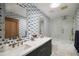 Stylish bathroom with patterned wallpaper, double sink vanity with navy cabinets, and glass enclosed shower at 5812 N 44Th Pl, Phoenix, AZ 85018