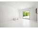 Bedroom with white walls and floors, two white ottomans, and sliding glass door opening to the backyard at 6740 E Presidio Rd, Scottsdale, AZ 85254