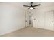 A carpeted bedroom featuring a ceiling fan, closet, and an adjacent doorway and staircase at 6841 E Osborn Rd # C, Scottsdale, AZ 85251