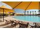 Resort-style community pool with numerous lounge chairs, shaded umbrellas, and inviting turquoise water at 7681 W Meadowlark Way, Florence, AZ 85132