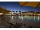 Inviting community pool at dusk, featuring comfortable lounge chairs, palm trees, and a well-lit clubhouse at 7681 W Meadowlark Way, Florence, AZ 85132