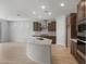 Modern kitchen features stainless steel appliances, center island with sink and white countertops, and stylish wood flooring at 7681 W Meadowlark Way, Florence, AZ 85132