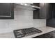 Close up of gas range, hood, white backsplash and granite countertops in modern kitchen at 7723 W Cactus Wren Way, Florence, AZ 85132