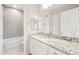 Modern bathroom showcasing white cabinets, granite countertops, and a tub with gray accent tiles at 7836 W Mockingbird Way, Florence, AZ 85132