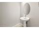 A pedestal sink with oval mirror in a neutrally painted powder room at 7836 W Mockingbird Way, Florence, AZ 85132