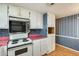 Compact kitchen equipped with white cabinets, electric range, and microwave; highlighted by pink countertops and patterned wallpaper at 8600 E Broadway Rd # 28, Mesa, AZ 85208