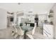 Dining room with sleek white chairs set around glass table, open to a modern kitchen at 10505 W Wilshire Dr, Avondale, AZ 85392