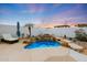 Backyard desert landscape featuring a serene pool with a charming waterfall and seating area at 10505 W Wilshire Dr, Avondale, AZ 85392