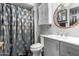 Bathroom featuring a modern vanity, a round mirror, white toilet, and a shower with a patterned curtain at 12402 N 36Th Dr, Phoenix, AZ 85029