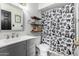 Bathroom featuring a modern vanity, decorative mirror, floating shelves, and a patterned shower curtain at 12402 N 36Th Dr, Phoenix, AZ 85029