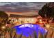 Backyard pool with spa, lounge chairs, outdoor kitchen and patio at twilight at 1356 E Desert Flower Ln, Phoenix, AZ 85048