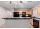 Well-lit kitchen features wood cabinets, an island, tile flooring, and black appliances at 1422 S 231St Ln, Buckeye, AZ 85326