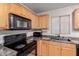 Bright kitchen with wood cabinets, black appliances, tile floors, and granite countertops at 1422 S 231St Ln, Buckeye, AZ 85326