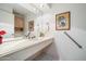 Well-lit bathroom features a long vanity with a mirror and an artistic touch with a framed print and flowers at 14710 W Yosemite Dr, Sun City West, AZ 85375