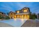 Two-story home with a three-car garage, showcasing traditional architecture and warm exterior lighting at dusk at 1473 E Mead Dr, Chandler, AZ 85249