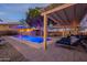 Inviting backyard pool at dusk features lounge chairs, a covered patio, and ambient lighting at 1473 E Mead Dr, Chandler, AZ 85249