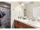 Bright bathroom features double sinks, tile countertops, and a decorative shower curtain at 15620 W Meadowbrook W Ave, Goodyear, AZ 85395