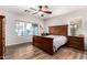 Cozy bedroom with hardwood floors, a dark wood bed frame, and a window offering a view of the backyard at 15620 W Meadowbrook W Ave, Goodyear, AZ 85395