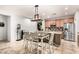 Open kitchen and dining area showcasing a center island with bar seating, stainless steel appliances, and modern light fixtures at 15620 W Meadowbrook W Ave, Goodyear, AZ 85395