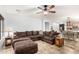 Open concept living room showcasing a large sectional sofa, tile flooring, and seamless flow into the dining and kitchen areas at 15620 W Meadowbrook W Ave, Goodyear, AZ 85395