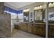 Primary bathroom with dual sinks, wooden cabinets, granite counters, and a separate shower area at 16606 S 15Th Ln, Phoenix, AZ 85045