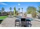 Backyard poolside dining space provides a cool spot to relax with an umbrella and nearby palm trees at 16646 S 16Th St, Phoenix, AZ 85048