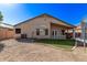 Rear exterior featuring a well-maintained yard, covered patio, and gravel landscaping for outdoor relaxation at 17574 W Corrine Dr, Surprise, AZ 85388