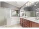 Bathroom featuring double sinks, wood cabinets, and a walk-in shower at 17574 W Corrine Dr, Surprise, AZ 85388