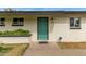 Close up of a home's entry with a teal door, white brick, and manicured landscaping at 1824 W State Ave, Phoenix, AZ 85021