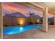 Inviting backyard pool area featuring a sparkling pool, covered patio, and lush landscaping with sunset view at 18259 W Buena Vista Dr, Surprise, AZ 85374