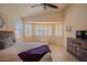 Bedroom with a ceiling fan, shuttered windows, bench seat, and wood laminate floors at 18259 W Buena Vista Dr, Surprise, AZ 85374