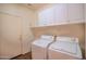 Clean laundry room with a washer, dryer, and overhead storage cabinets at 18259 W Buena Vista Dr, Surprise, AZ 85374