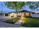 Charming single-story home with a well-manicured lawn and a spacious two-car garage, illuminated at dusk at 1849 E 2Nd Pl, Mesa, AZ 85203