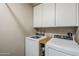 Functional laundry room featuring a side-by-side washer and dryer with upper cabinets at 1849 E 2Nd Pl, Mesa, AZ 85203