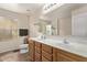 A well-lit bathroom featuring a double vanity, toilet, and a large mirror over the countertop at 18537 W Mariposa Dr, Surprise, AZ 85374