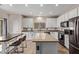 Kitchen with white cabinets, stainless steel appliances, a center island with seating, and tile flooring at 18537 W Mariposa Dr, Surprise, AZ 85374