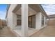 View of a backyard patio area with a stucco wall, sliding glass doors, and a view of the home's kitchen at 20318 W Turney Ave, Buckeye, AZ 85396