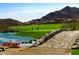 Scenic golf course view with lush green grass, lake and mountain views and a stone bridge in the foreground at 20318 W Turney Ave, Buckeye, AZ 85396