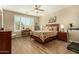 Comfortable bedroom with wood-look floors, ceiling fan, large window with shutters, desk, and a patterned comforter at 21362 N 260Th Ln, Buckeye, AZ 85396