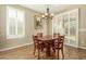 Cozy dining area featuring a wood table, four chairs, elegant chandelier, and view to the outdoors through shuttered doors at 21362 N 260Th Ln, Buckeye, AZ 85396