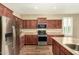 Modern kitchen featuring stainless steel appliances, wood cabinets, and a center island with sink at 21362 N 260Th Ln, Buckeye, AZ 85396