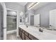 Modern bathroom featuring a double sink vanity, decorative mirror, and a shower with glass doors at 2592 E Torrey Pines Ln, Chandler, AZ 85249