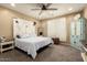 Comfortable bedroom featuring a large bed with a decorative headboard, ceiling fan and neutral decor at 25955 W Deer Valley Rd, Buckeye, AZ 85396