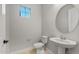 A half bathroom with a pedestal sink and a round mirror at 26657 W Renee Dr, Buckeye, AZ 85396